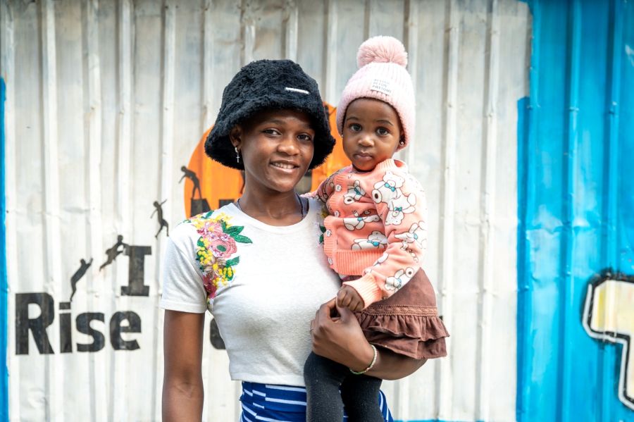 Gertrude mit Kind Openda Gertrude mit ihrer Tochter vor der Bibliothek des Projektes INUA